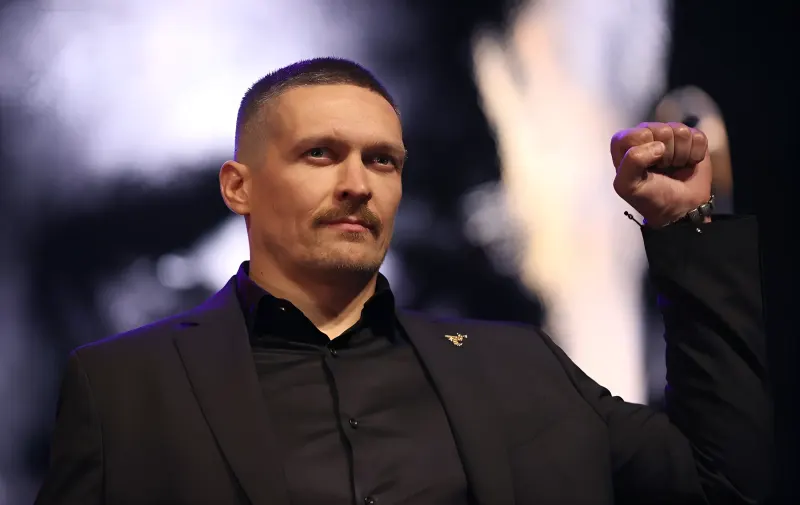 Олександр Усик у чорному костюмі з золотим елементом на лацкані під час виходу на бій біля пірамід Гізи