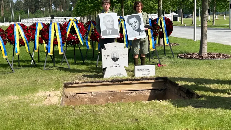 Ритуал перезахоронения на НВМК: участники держат портреты Андрея Мельника и Софии Федак-Мельник у открытой могилы с венками