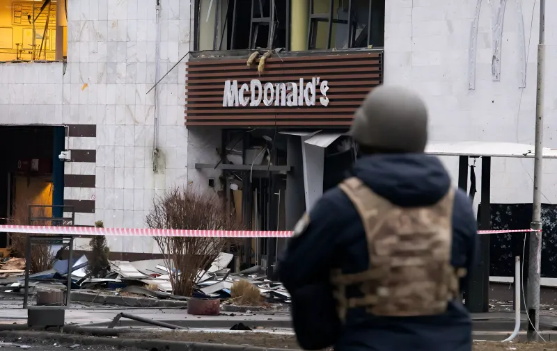Разрушенный фасад здания с вывеской McDonald's на фоне военного разрушения в Киеве
