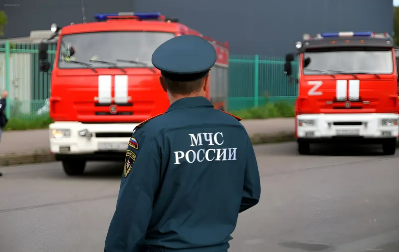 Сотрудник МЧС России стоит спиной к камере, на фоне видны пожарные машины, работающие на месте инцидента в Чебоксарах