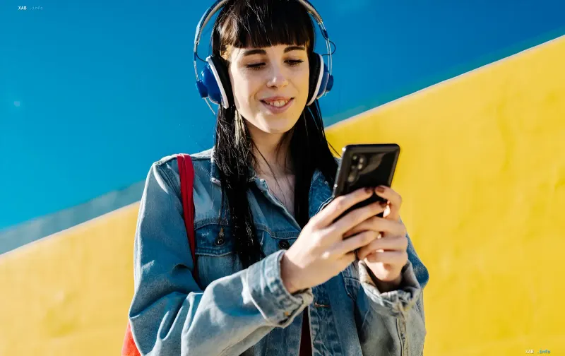 Молодая блогерша с наушниками и смартфоном на фоне яркой стены — символ легального заработка в соцсетях и важности уплаты налогов