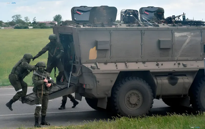 Ukrainian soldiers in camouflage disembark from a BTR-80 armored personnel carrier against a backdrop of fields, symbolizing the fierce battles for Kinburn Spit and the strategic foothold