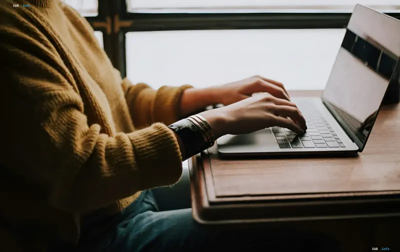 Person typing on a MacBook, illustrating the topic of touch-enabled MacBook without M6 chips and Apple's AI strategy