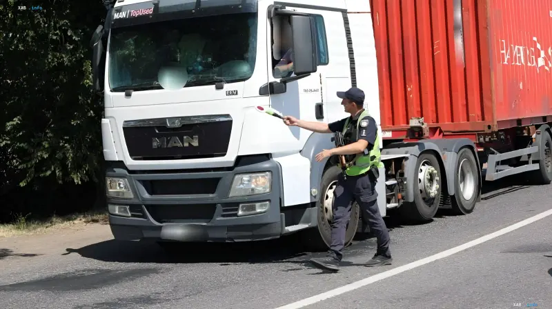 Polizist hält einen weißen MAN-LKW mit rotem Container auf einer Straße in der Oblast Odessa an, da der Schwerlastverkehr bei Hitze eingeschränkt ist