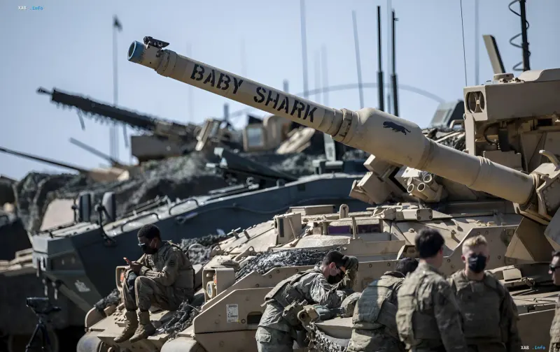 Американские танки Abrams с надписью 'Baby Shark' и военнослужащие в камуфляже на учениях, демонстрируя готовность США защищать Балтию