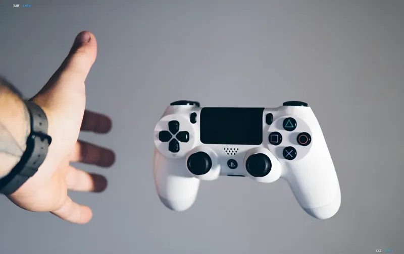 White PlayStation 5 controller and a reaching hand — symbolizing the shift from physical discs to digital games