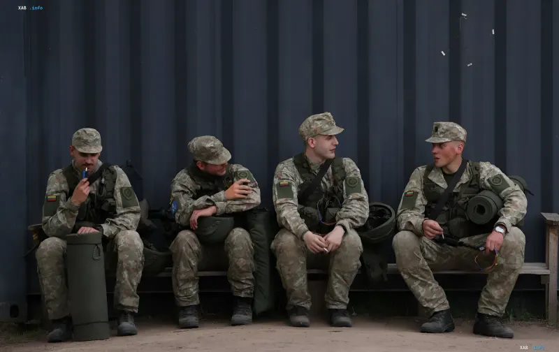 Lithuanian soldiers in camouflage uniforms sit on a bench, discussing NATO strategy in the context of the possible lifting of the ban on nuclear weapons