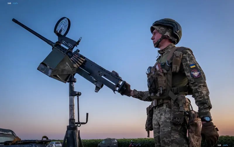 Ukrainian border guard with a machine gun against a sunset backdrop, ready to repel drone attacks