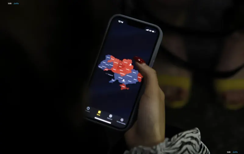 Frau betrachtet Ukraine-Karte mit Warnzonen auf Smartphone im Dunkeln — Illustration der neuen Überlebensregel in Sumy bei Flugbombengefahr