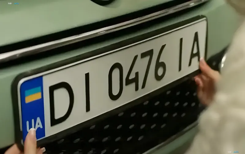 Person installing a desired license plate on a car in Ukraine