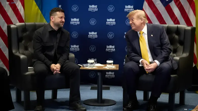 Володимир Зеленський та Дональд Трамп сидять у кріслах на тлі прапорів США та України, усміхаючись одне одному під час зустрічі на саміті НАТО