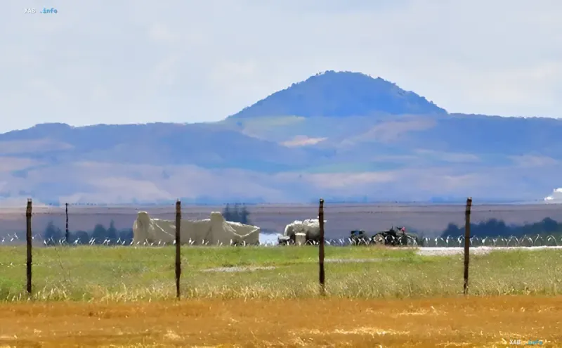 Field with military installations against mountainous backdrop — symbol of geopolitical tension over S-400 and F-35