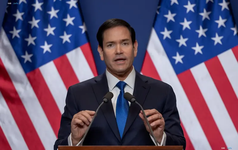 Marco Rubio speaking in front of American flags, symbolizing US influence on Venezuela's politics