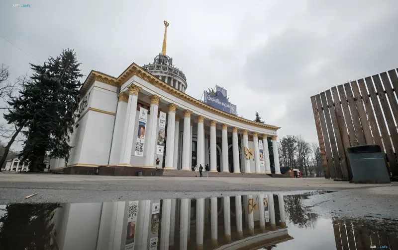 Павильон ВДНХ в Киеве с символом серпа и молота на куполе, отражающийся в луже на асфальте