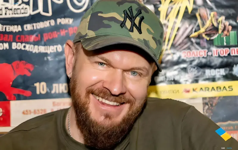 Александр Положинский, фронтмен группы «Тартак», улыбается на фоне музыкальных афиш, обсуждая личную жизнь в условиях войны