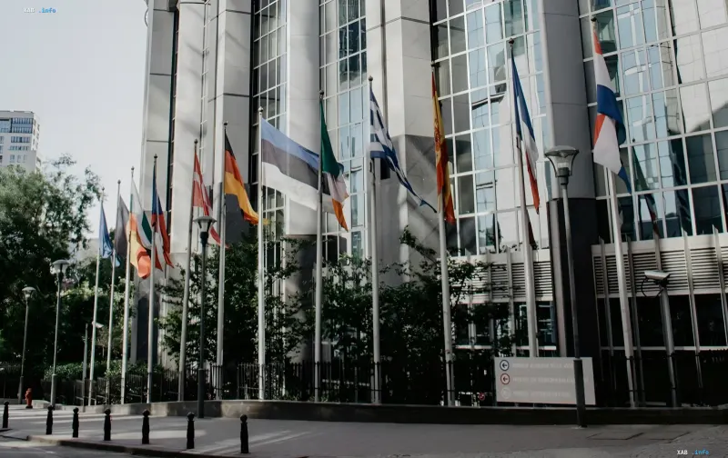 Estonian flag among EU member flags outside the European Parliament in Brussels, symbolizing the demand to freeze IOC funding due to Russian athletes' return