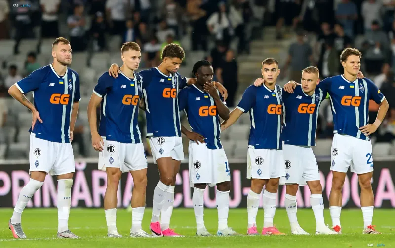 Spieler des FC Dynamo Kiew in blauen Trikots mit GG-Sponsorenlogo stehen vor einem Spiel auf dem Feld