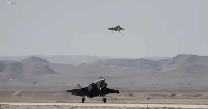 Истребители F-35 на взлетно-посадочной полосе: один самолет взлетает, другой готовится к старту на фоне пустынного ландшафта