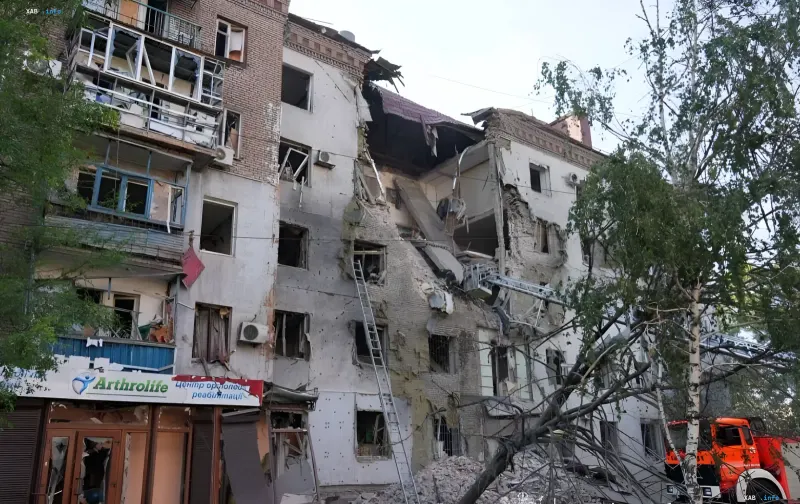 Destroyed five-story building in the center of Zaporizhzhia after an attack, debris and rescue equipment visible