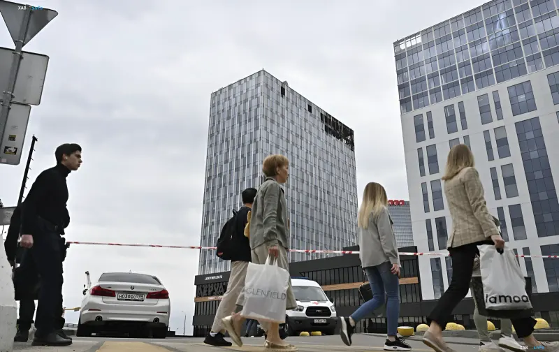 Люди з сумками проходять повз будівлі в сучасному місті, ілюструючи тему відтоку населення та пошуку нових можливостей за кордоном