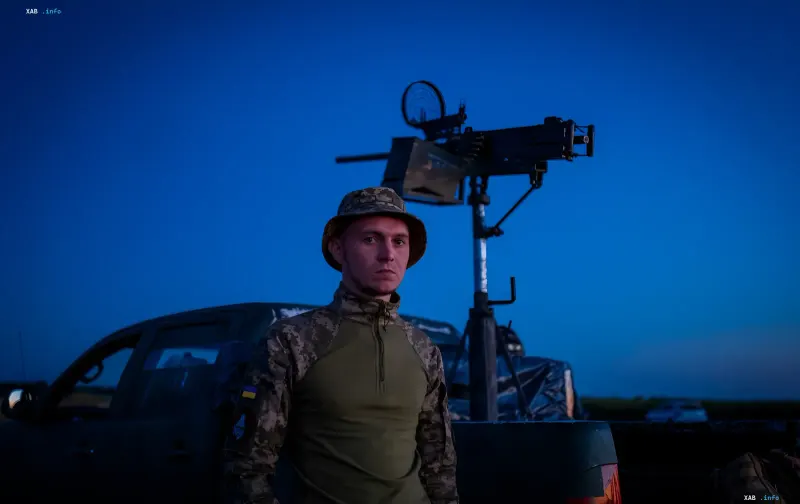 Ukrainian soldier standing by an air defense system against a night sky, ready to counter a massive drone attack