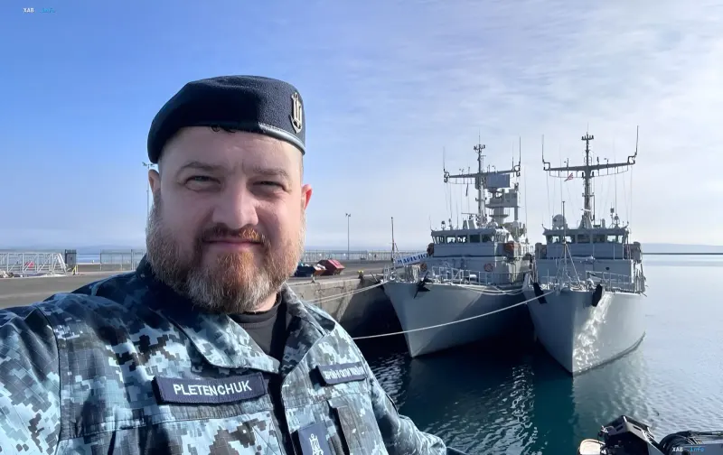 Ukrainian sailor in camouflage uniform in front of naval ships at the dock, symbolizing the readiness of the Ukrainian Navy to respond to Iran's threats after the Caspian Sea incident