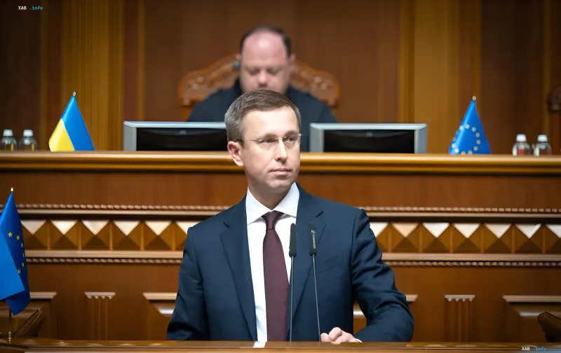 Ukrainian Finance Minister Serhiy Marchenko delivers a speech in parliament against the backdrop of Ukrainian and EU flags, discussing the war budget and funding for 2026