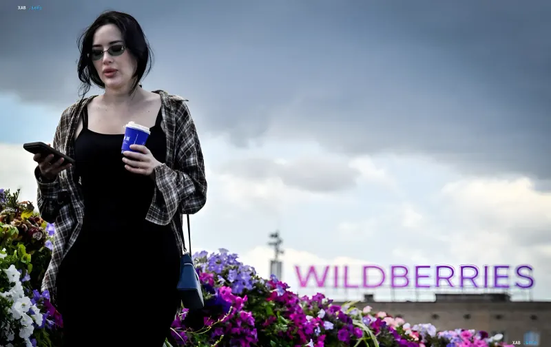 Woman in sunglasses holding a smartphone and coffee in front of the Wildberries logo, illustrating new safety rules for employees