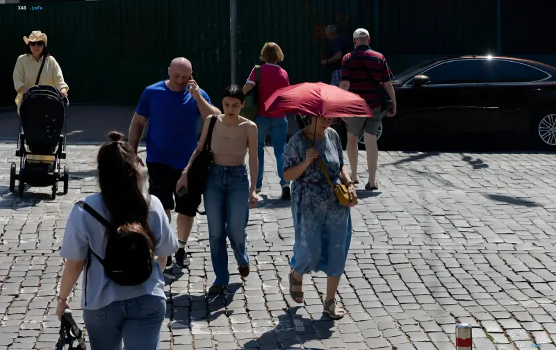 Pedestrians on Kyiv street, woman with red sun umbrella, critical air quality deterioration