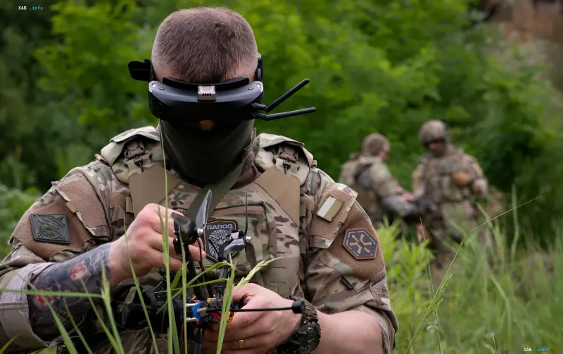 Український бійць у сучасному камуфляжі та захисній броні з патчем «RAJOG» на грудях, керує FPV-дроном у польових умовах — приклад інтеграції вітчизняних технологій у спорядження ЗСУ