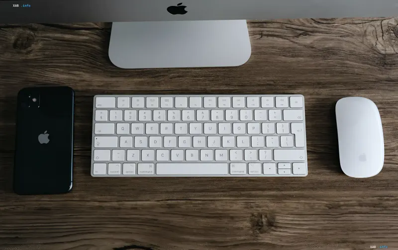 Arbeitsplatz mit iPhone, Tastatur und Maus von Apple auf Holztisch — Symbol des Trade-In-Programms mit erhöhten Auszahlungen bis zu 1300 Dollar