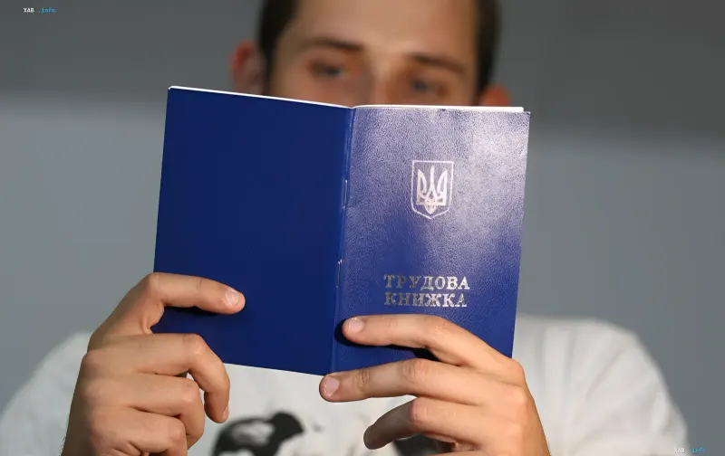 Людина тримає відкриту трудову книжку України, що символізує пошук втраченого стажу для пенсії