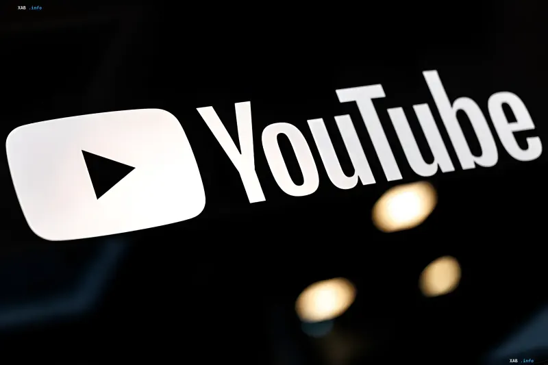 Логотип YouTube на черном фоне с размытыми огнями, символизирующий новые правила монетизации и борьбу с AI-контентом в 2026 году