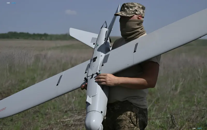 Военнослужащий держит разведывательный дрон на фоне поля, иллюстрируя тему отмены «Дронницы-2026» в Великом Новгороде из-за угрозы украинских ударов