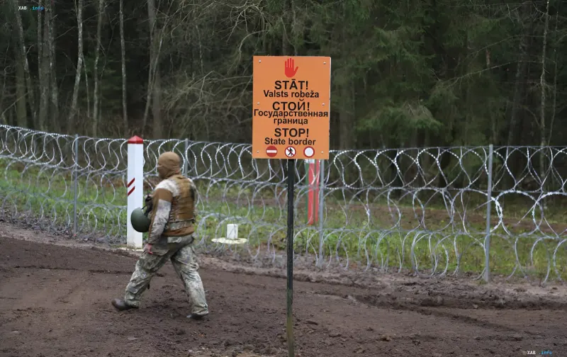 Soldat patrouilliert verstärkte litauische Grenze mit Stacheldraht und Warnschild