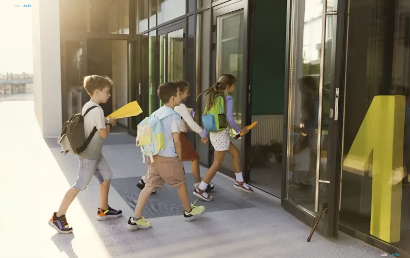 Schoolchildren with backpacks entering a modern school in Kyiv, illustrating the theme of in-person learning on September 1, 2026, despite risks from incomplete repairs after attacks