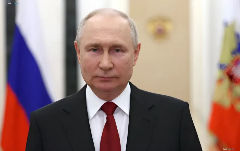 Wladimir Putin im Anzug vor der russischen Flagge, verbunden mit seinem Besuch auf Iturup und dem territorialen Streit mit Japan