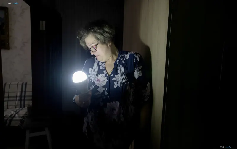 Woman with flashlight in dark room after power outage in Chernihiv due to attack on energy infrastructure