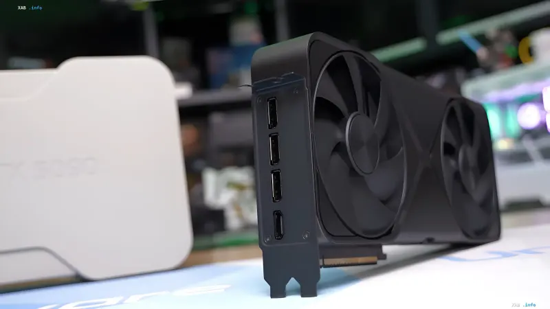 Видеокарта NVIDIA GeForce RTX 5090 с тремя вентиляторами и портами DisplayPort на фоне размытого игрового оборудования — иллюстрация к тестам 6K-гейминга, где флагману не хватает мощности