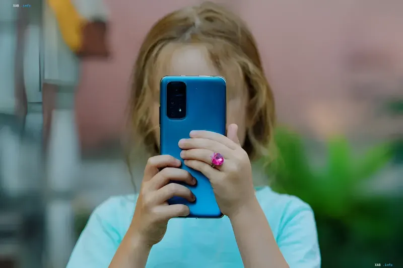 Підліток тримає смартфон із синім чохлом, що символізує використання ChatGPT для навчання та контролю з боку батьків