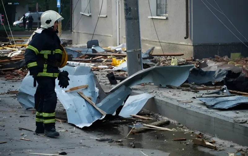 Rettungskraft in Schutzausrüstung begutachtet die Zerstörungen nach einem Angriff auf Sschytomyr: verbogenes Metall, Trümmer und Wasser am Einschlagsort