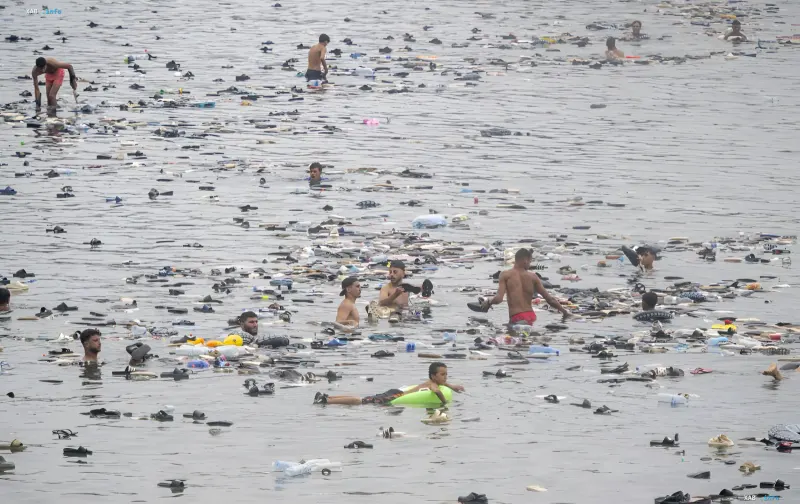 Migranten schwimmen im Wasser vor der Küste von Murcia, umgeben von einer großen Menge weggeworfener Schuhe nach der Ankunft eines Bootes