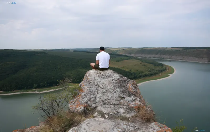 Man sitting on a rock overlooking the winding Dniester river and Podillia hills near Bakota — a spot to recharge