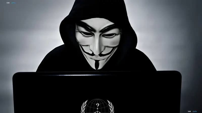 Аноним в маске Гая Фокса за ноутбуком с логотипом Anonymous