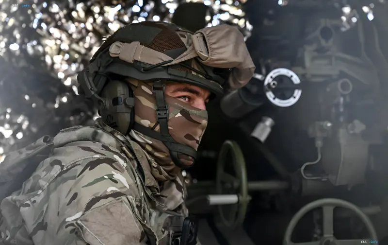 Ukrainischer Soldat in Tarnkleidung und Taktikhelm neben einer Flak in einem bewaldeten Gebiet