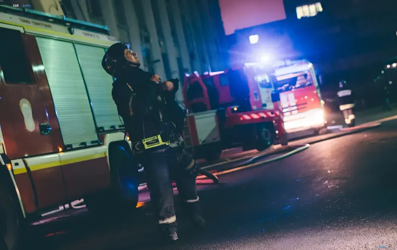 Firefighter in protective gear at the site of a drone strike on an Ozon logistics center at night
