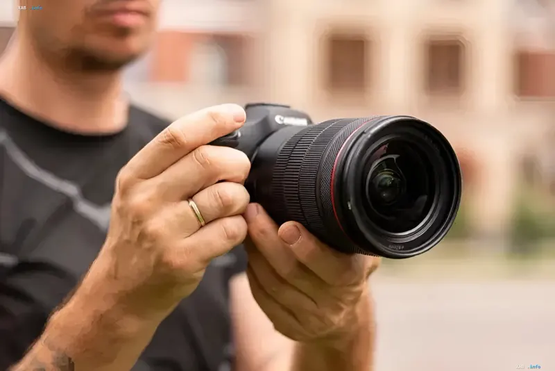 Фотограф держит профессиональную цифровую камеру Canon с объективом серии L