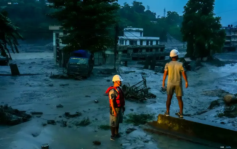 Rescue workers in helmets assess the damage after floods and landslides in Nepal: mudflows, debris and damaged buildings