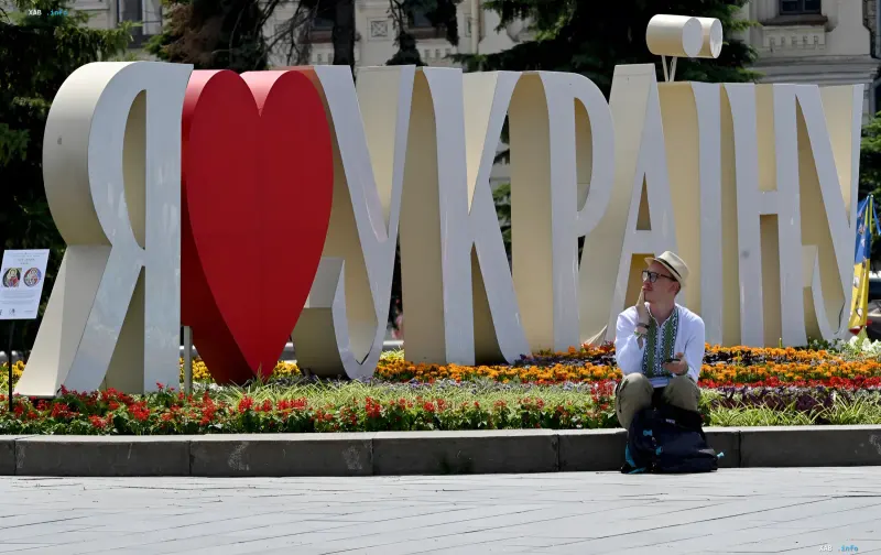 Ein Mann entspannt sich bei der Installation „Ich liebe die Ukraine“ vor einer blühenden Blumenbeet an einem warmen Sommertag in der Ukraine
