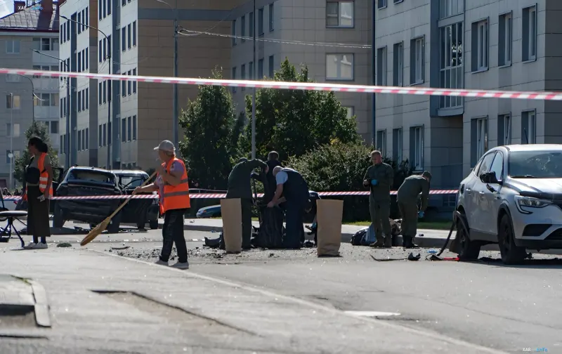 Место взрыва автомобиля в Петербурге: спасатели в оранжевых жилетах и военнослужащие убирают обломки за лентой оцепления